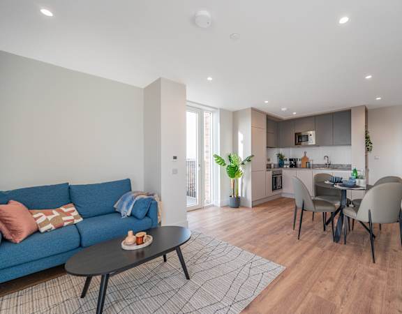 a living room with a blue couch and a table and a kitchen