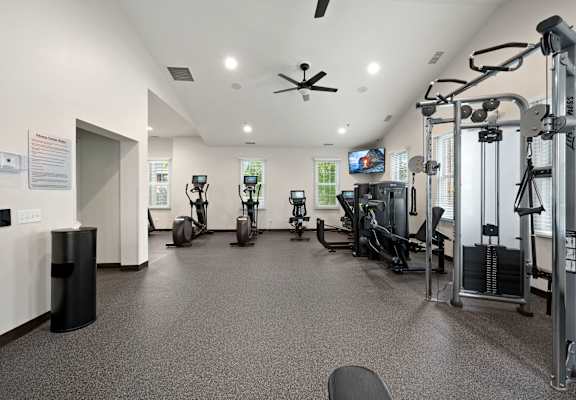 A gym with a variety of equipment including treadmills, weights, and a television.