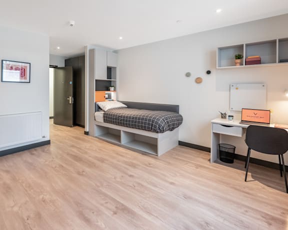 a bedroom with a desk and a bed in a small room