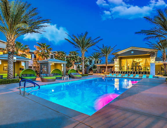A swimming pool surrounded by palm trees and lounge chairs.