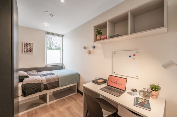 a bedroom with a bed and a desk with a laptop