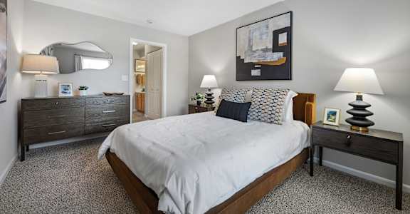 A bedroom with a large bed, a nightstand, and a dresser.