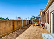 Thumbnail 3 of 5 - A backyard with a wooden fence and a picnic table.