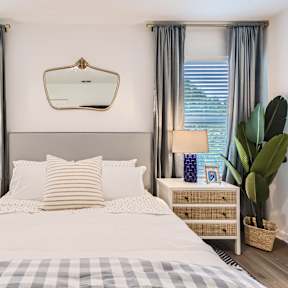 A bedroom with a large bed, two nightstands, and a mirror above the bed.
