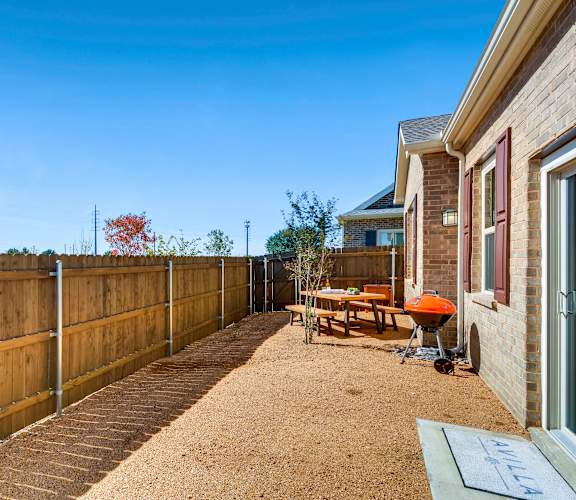 A backyard with a wooden fence and a picnic table.