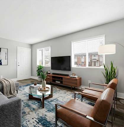 A living room with a grey couch, a brown leather chair, a coffee table, and a television.