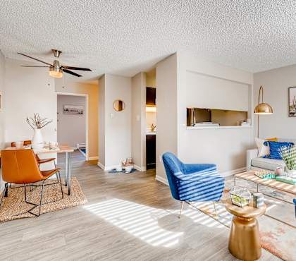 A living room with a white couch, blue armchair, and a coffee table at Mountain Vista Apartments, Lakewood, CO, 80228