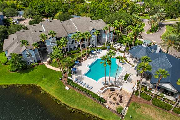 an aerial view of the resort style swimming pool and poolside patio with umbrellas