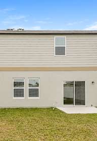A beige house with a white fence and a green lawn.