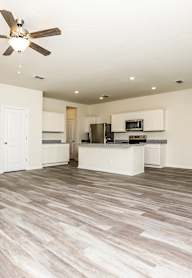A spacious room with a ceiling fan and lighting fixtures.