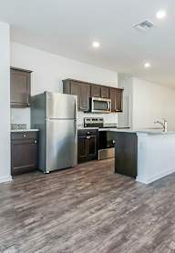 A kitchen with a refrigerator, microwave, and oven.