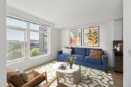 a living room with a blue couch and a green and white rug