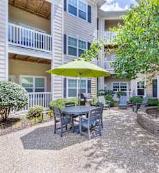 A patio with a table and chairs under a green umbrella.