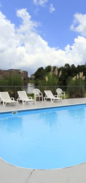 a swimming pool with chairs and a fence around it
