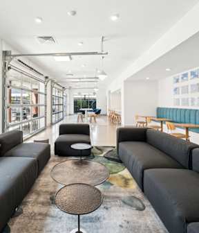 A modern living room with black leather couches and a round coffee table.