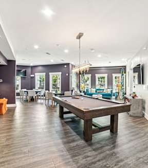 A room with a pool table and a bar area.