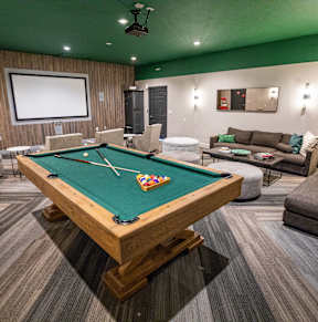 A pool table is in the middle of a room with a couch and a television.