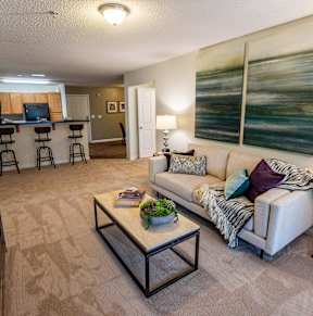 A living room with a couch, coffee table, and a painting on the wall.