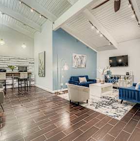 A living room with a blue couch and a dining table.