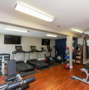 a gym with cardio equipment and weights on a wooden floor