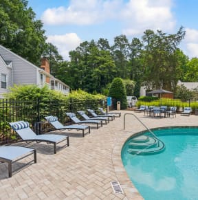 a swimming pool with lounge chairs next to a house at Lake Johnson Mews Apartments, PRG Real Estate Management, Raleigh, 27606