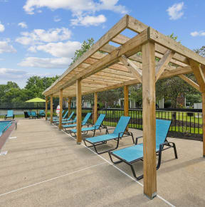 a row of blue lounge chairs next to a swimming pool