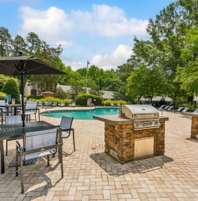 a backyard with a swimming pool and tables with umbrellas at Lake Johnson Mews Apartments, PRG Real Estate Management, Raleigh, 27606