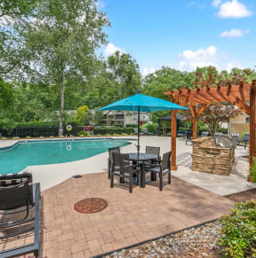 a backyard with a pool and patio with tables and umbrellas
