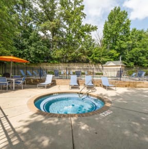 a jacuzzi and patio with chairs and umbrellas in a backyard