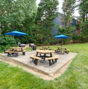 a patio with tables and umbrellas in a yard