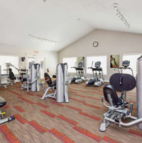 a gym with weights and cardio equipment in a building with white walls