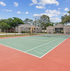 a tennis court with apartments in the background