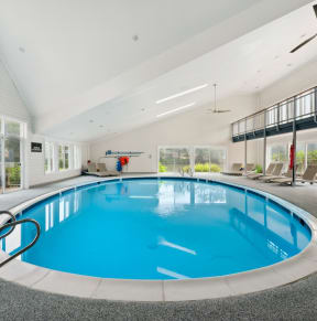 the indoor swimming pool is surrounded by windows and has a blue pool in the middle