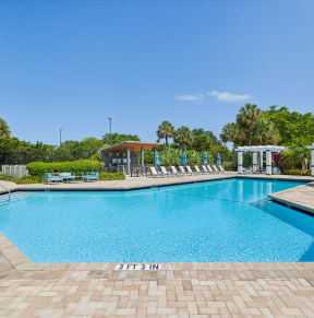 a large swimming pool with chairs around it in front of a house