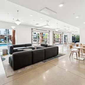 A modern living room with a black sofa and wooden chairs.