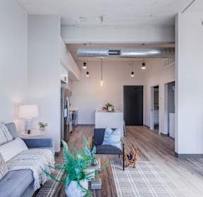 A living room with a grey couch and a painting on the wall.