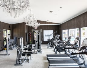 a gym with cardio machines and chandeliers