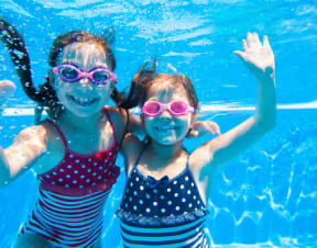two girls with goggles swimming in a pool