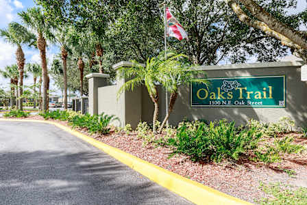 A street sign for Oaks Trail stands in front of a building.