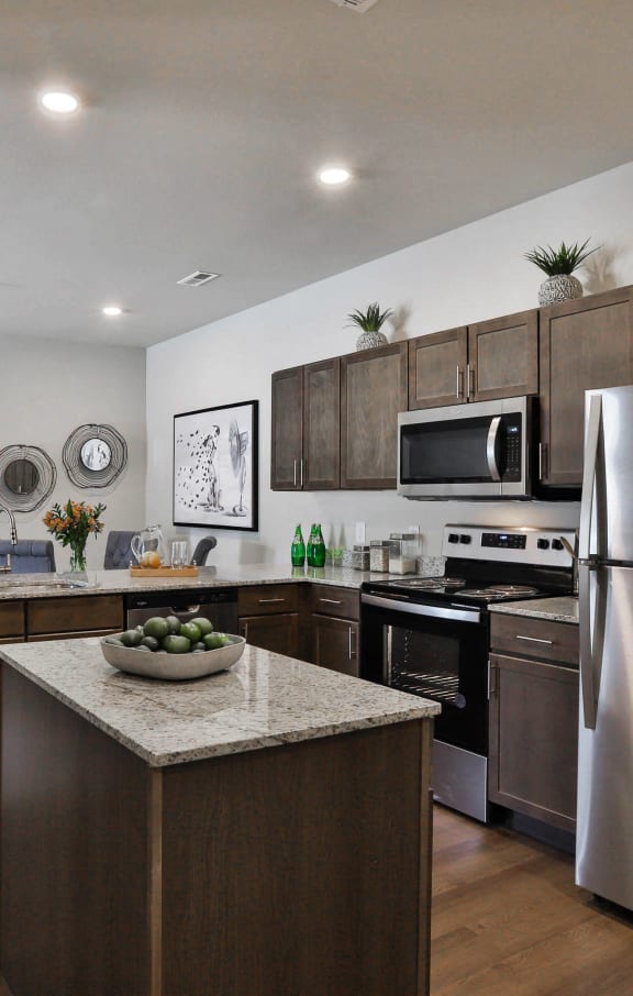 a living room with a large tv and a kitchen in the background  at Aventura at Hawk Ridge, Lake St Louis, 63367