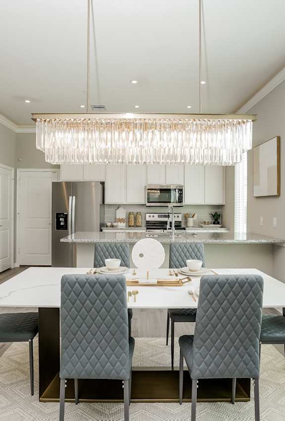 A modern dining room with a large table and grey chairs.
