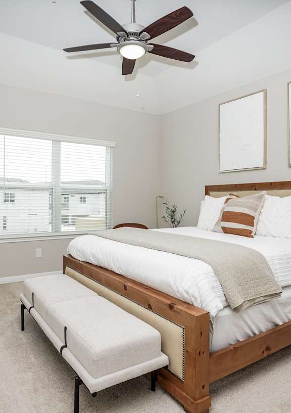 A bedroom with a large bed and a ceiling fan.