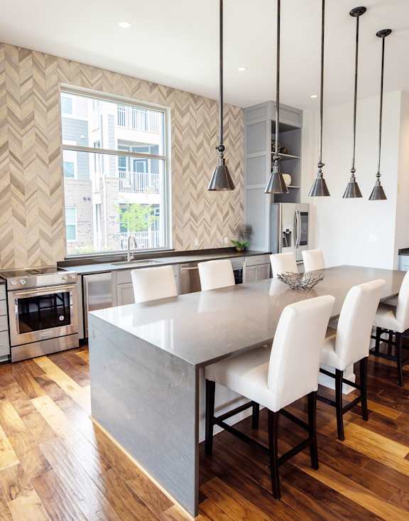 A modern kitchen with a wooden floor and a dining table with chairs.