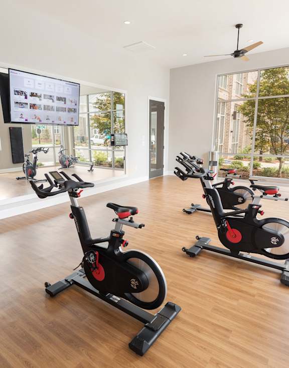 A gym with a row of stationary bikes and a mirror on the wall.