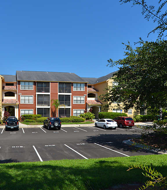 A parking lot in front of a building with cars parked.