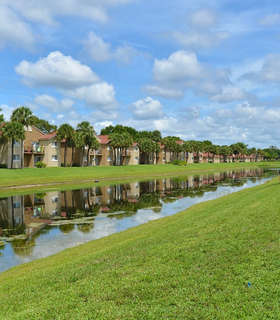a park bench sits on the grass next to a river