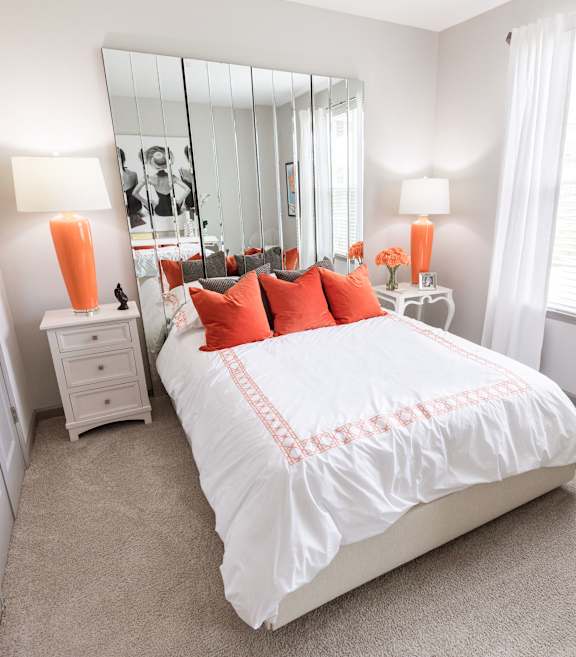 A bedroom with a large bed and a mirror on the wall.