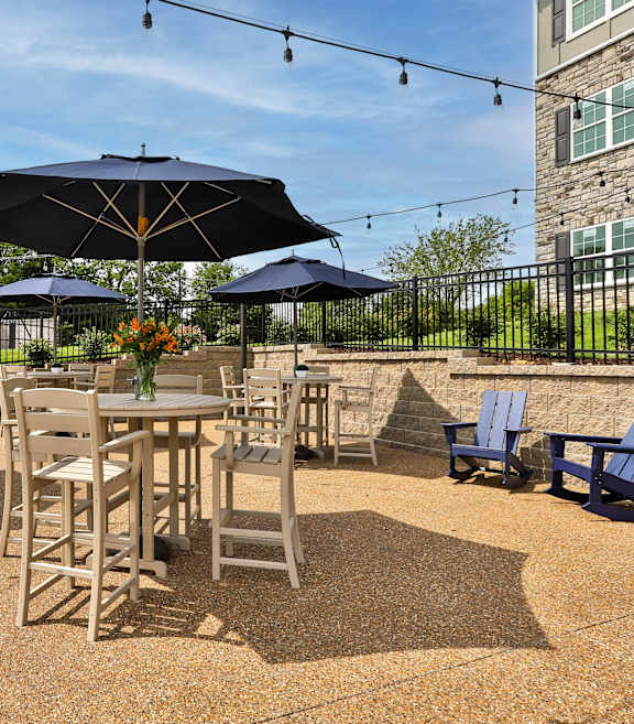 a patio with tables and chairs at the whispering winds apartments in pearland, tx  at Aventura at Hawk Ridge, Lake St Louis, MO, 63367