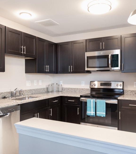 kitchen a kitchen with black cabinets and stainless steel appliances and granite counter tops at Cherry Street Lofts in Bridgeport, CT, 06605