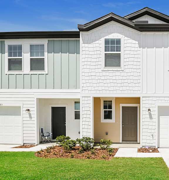 a row of townhomes with tan siding and white doors